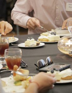 Small plates of delicate desserts sit at the center of a banquet table as people eat the main course.