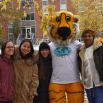 Four people in coats pose outside with MU's Truman the Tiger mascot, who is wearing an IEP T-shirt.