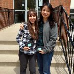 Two girls pose on the steps of the CELL building holding awards.