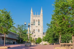 The tall, stone, ornate clock tower of Memorial Union sits at the end of a tree-line brick ped mall.